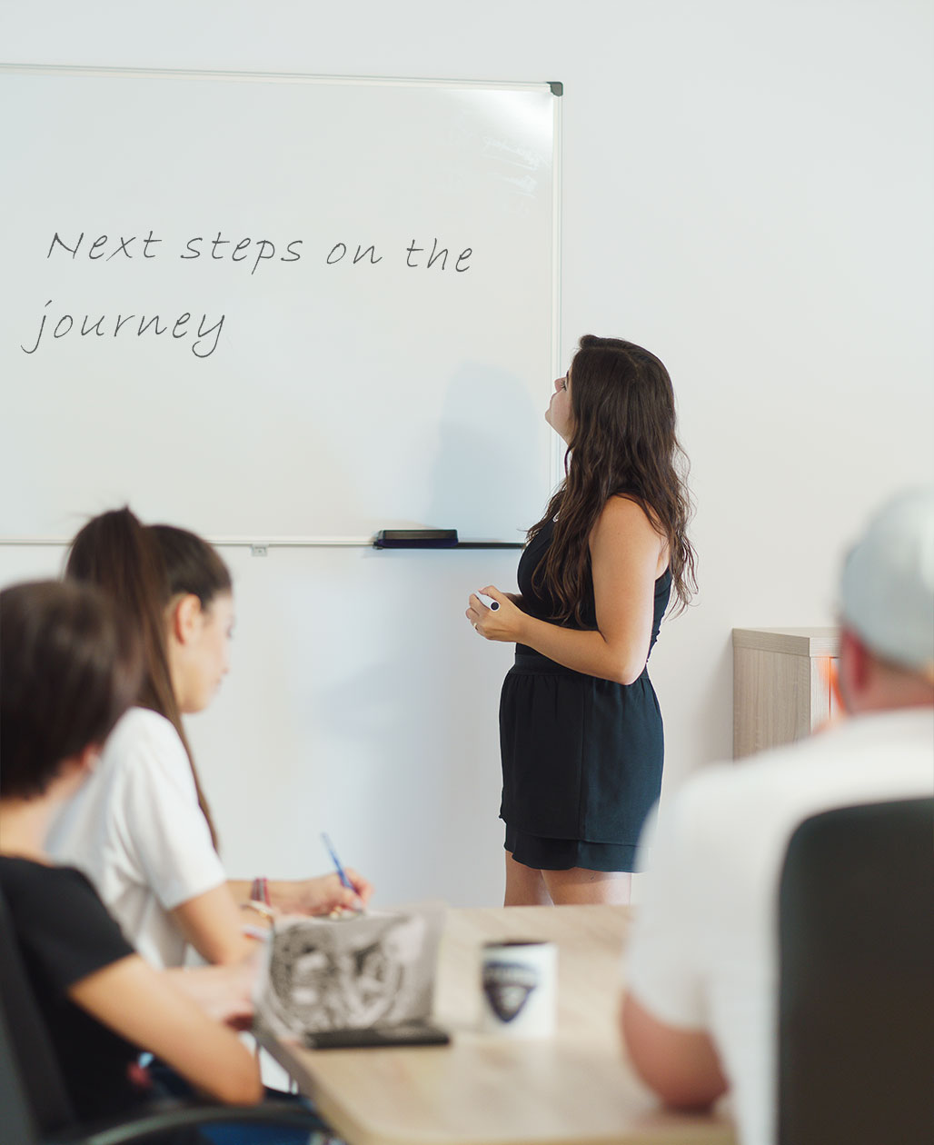 An employee standing in front of a whiteboard with the text Next Steps on the Journey written.